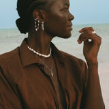 Woman wearing layered silver jewelry with chain earrings.