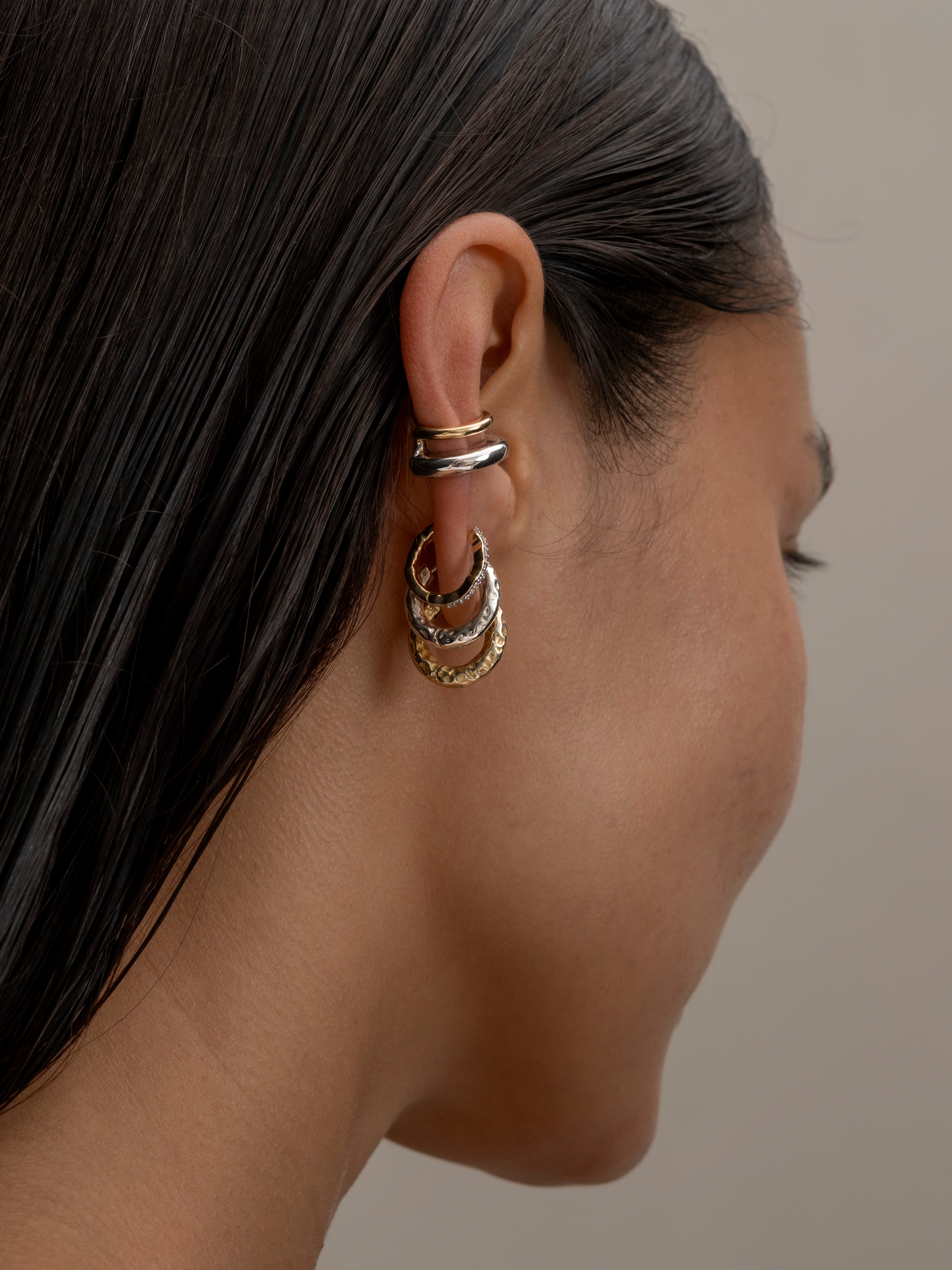 Woman wearing layered gold hoop earrings.