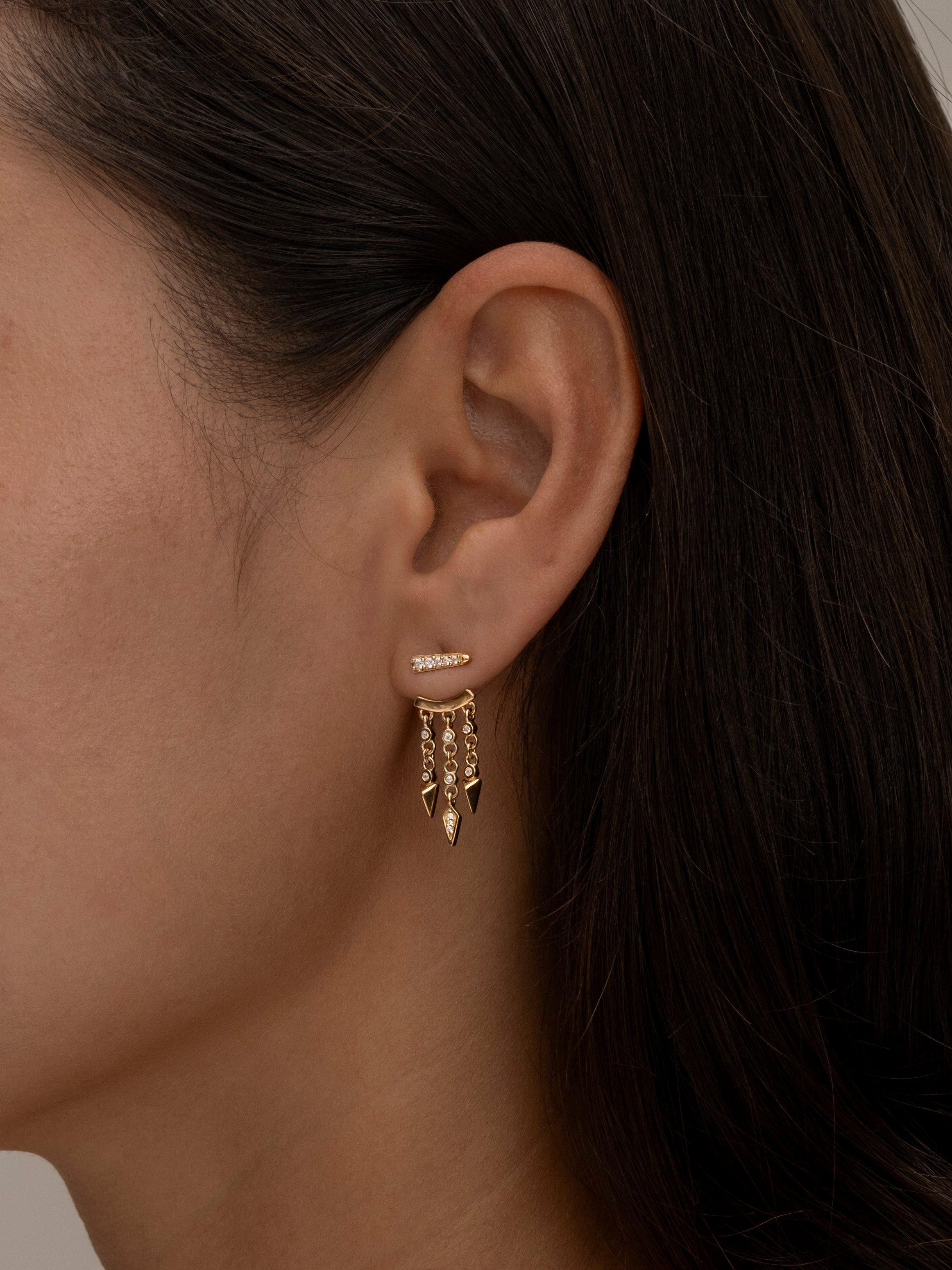 Side profile showing gold layered earrings on woman's ear.