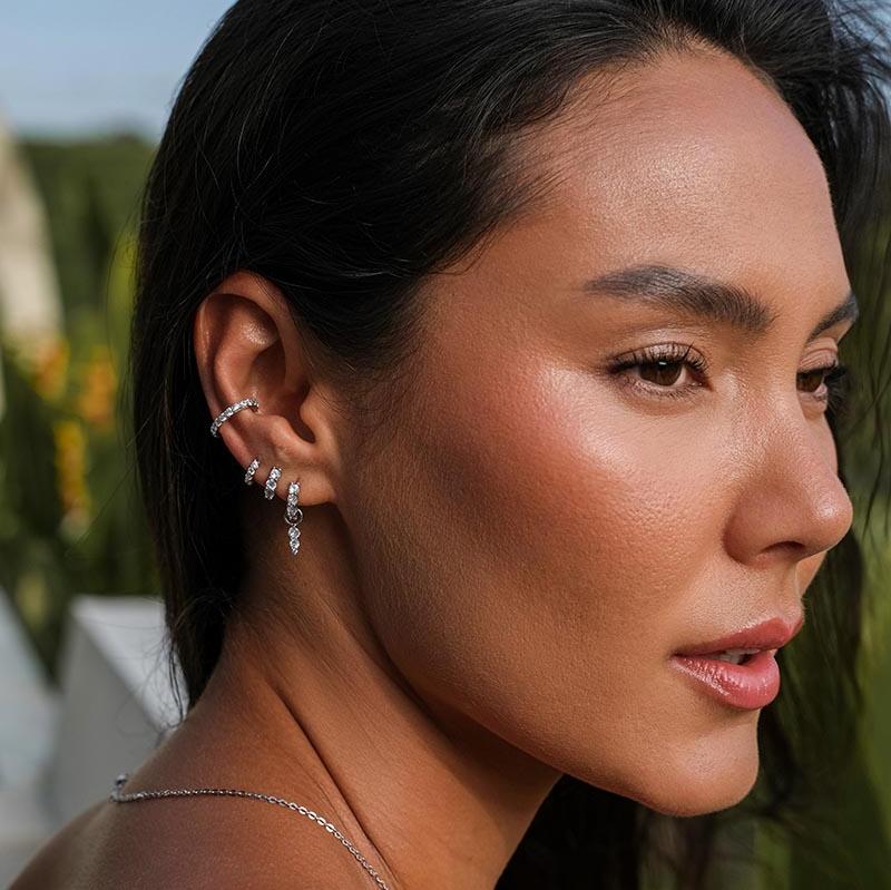 Portrait of a woman wearing diamond earrings and a silver necklace. 1