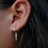 Close-up of ear with silver hoop & pointed drop earring.