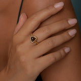 Woman wearing gold ring with a triangular brown gemstone.
