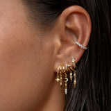 Gold and diamond dangling hoop earrings on a woman's ear.