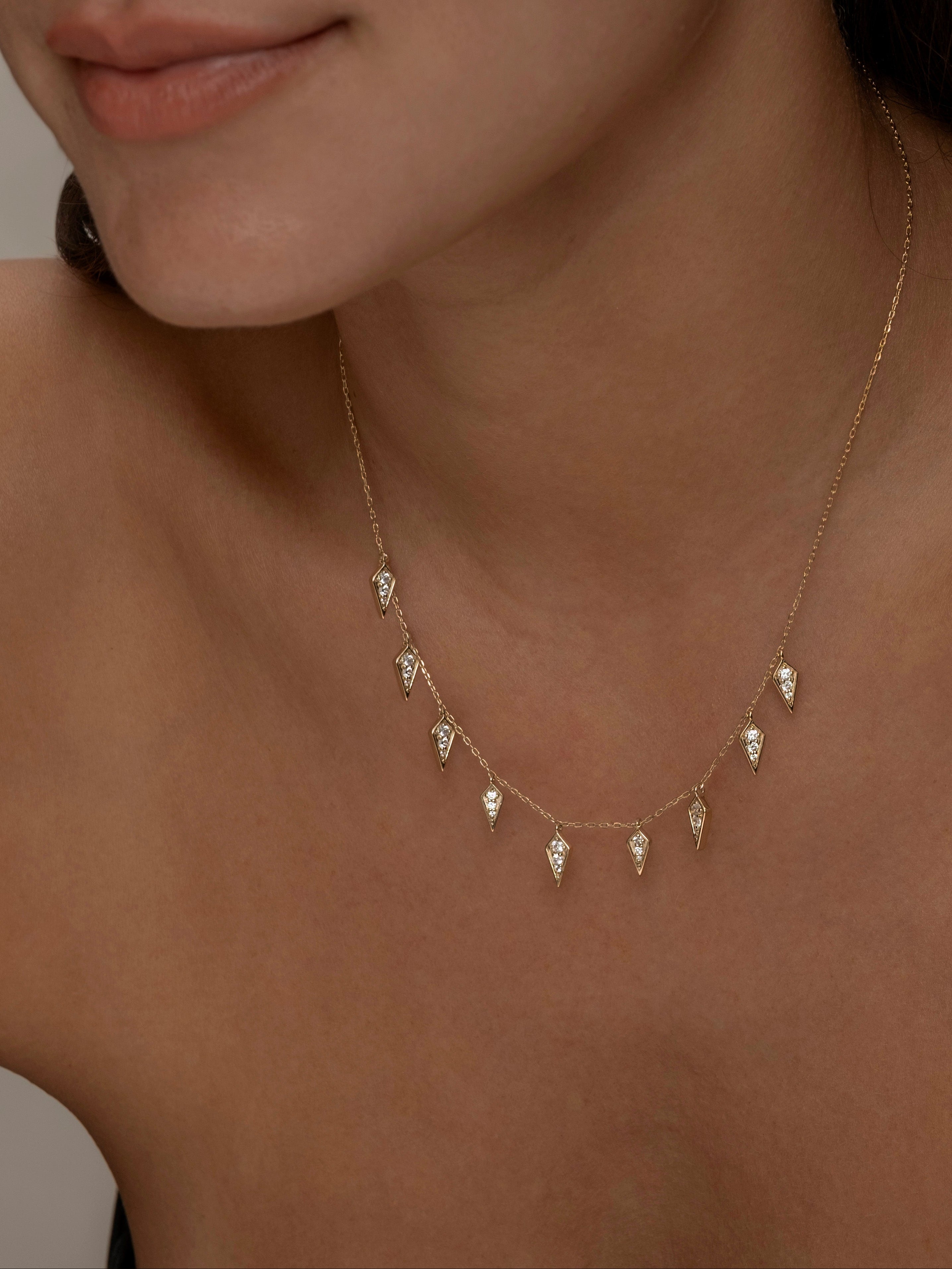 Close-up of gold Palma necklace with diamond-shaped charms on a woman.