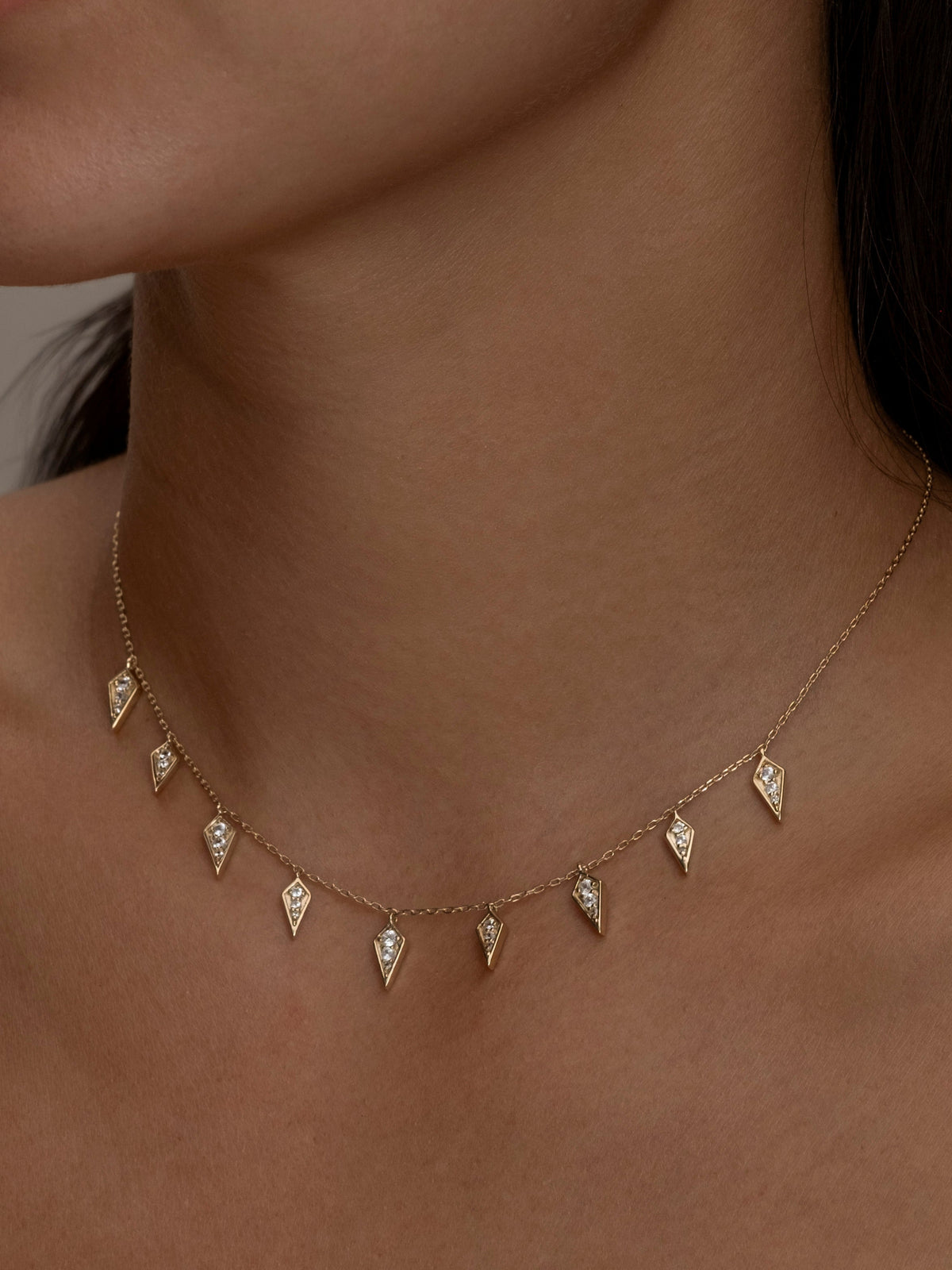 Gold Palma necklace with diamond-shaped charms on a woman.