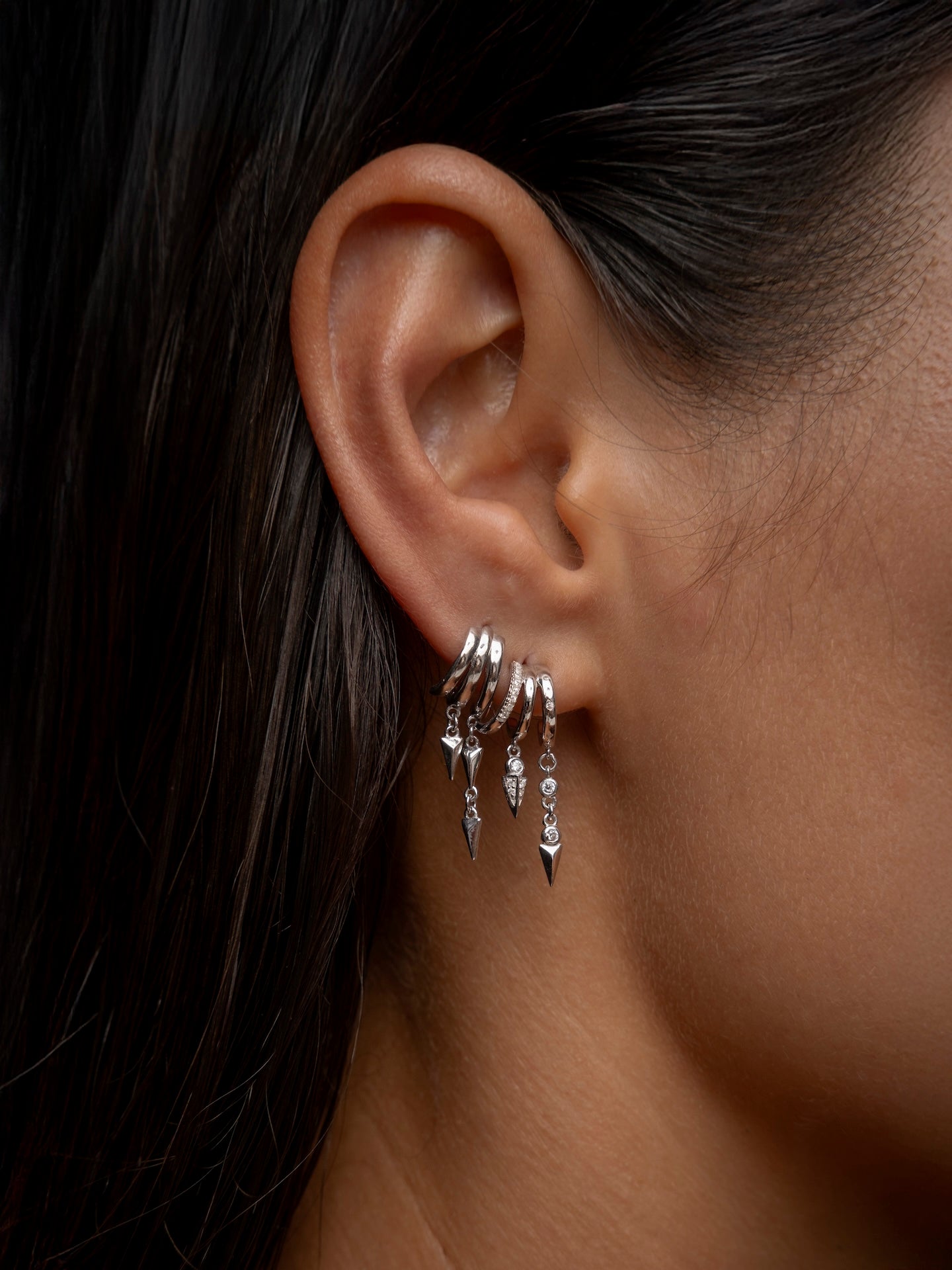 Silver Sienna-Lynx dangling hoop earrings on a woman's ear.