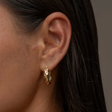 A woman's ear adorned with mini chateau hammered hoop earring