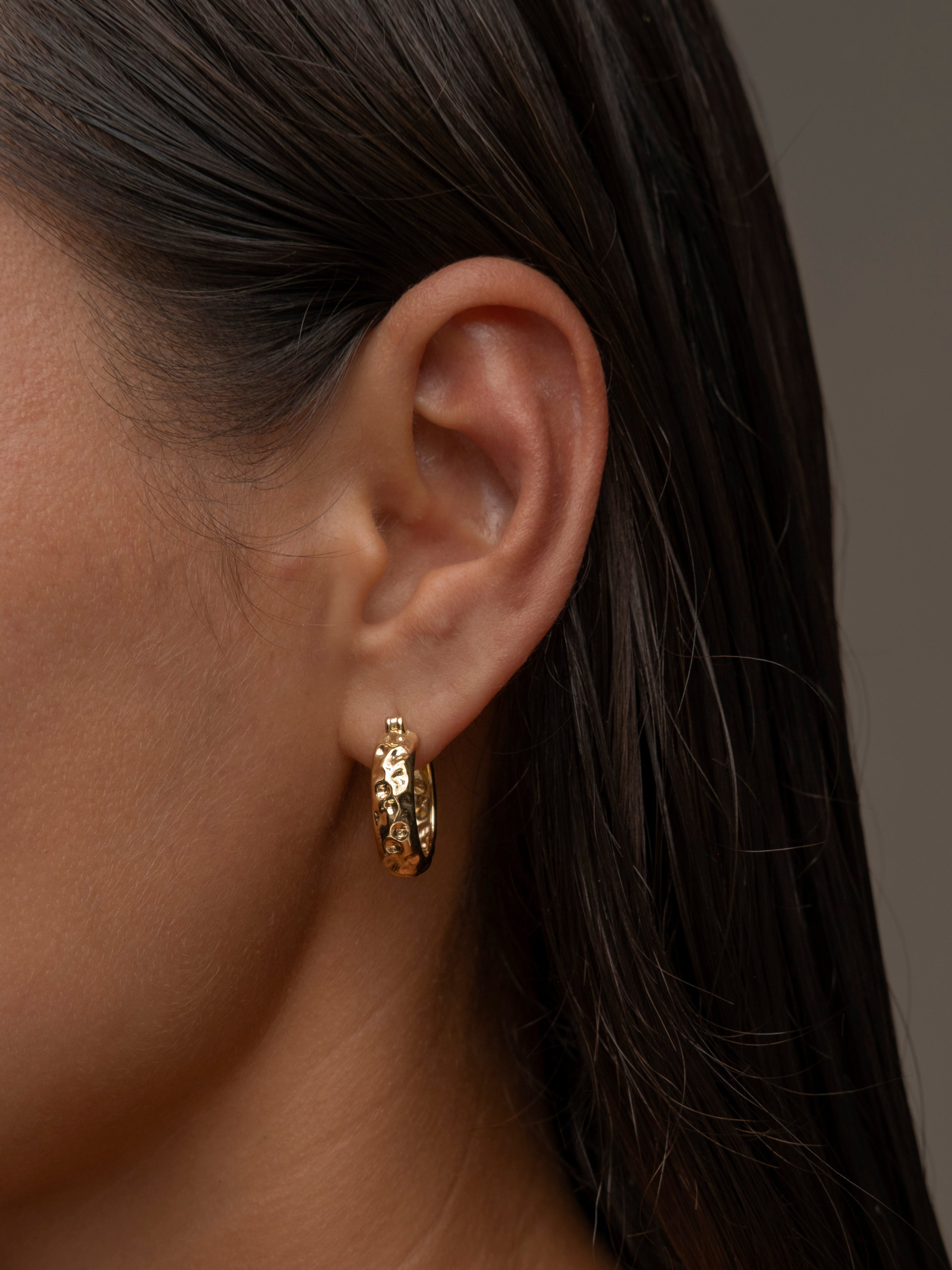 A woman's ear adorned with mini chateau hammered hoop earring