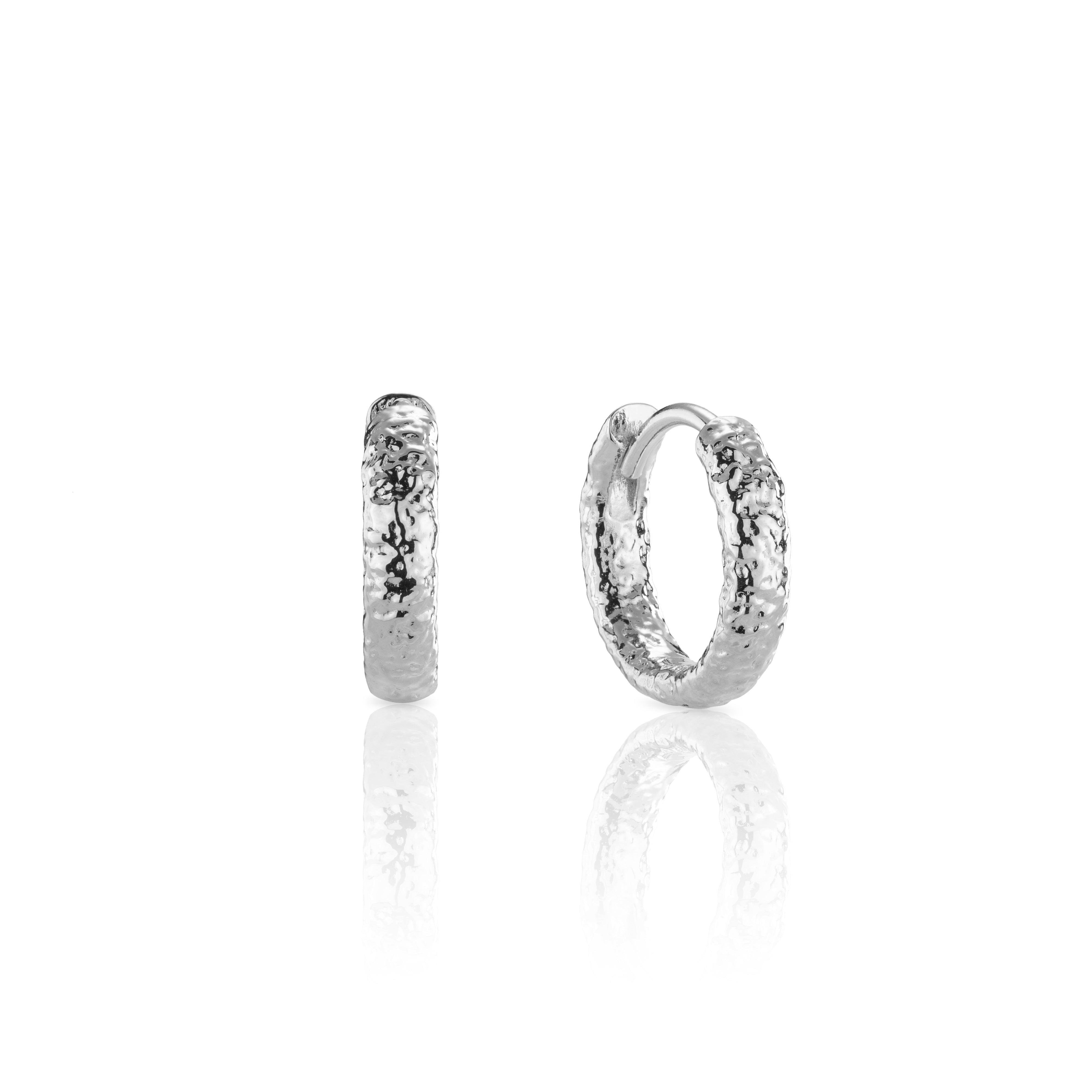 Pair of textured silver huggie hoop earrings on display.