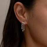 Side profile showing silver layered earrings on woman's ear.