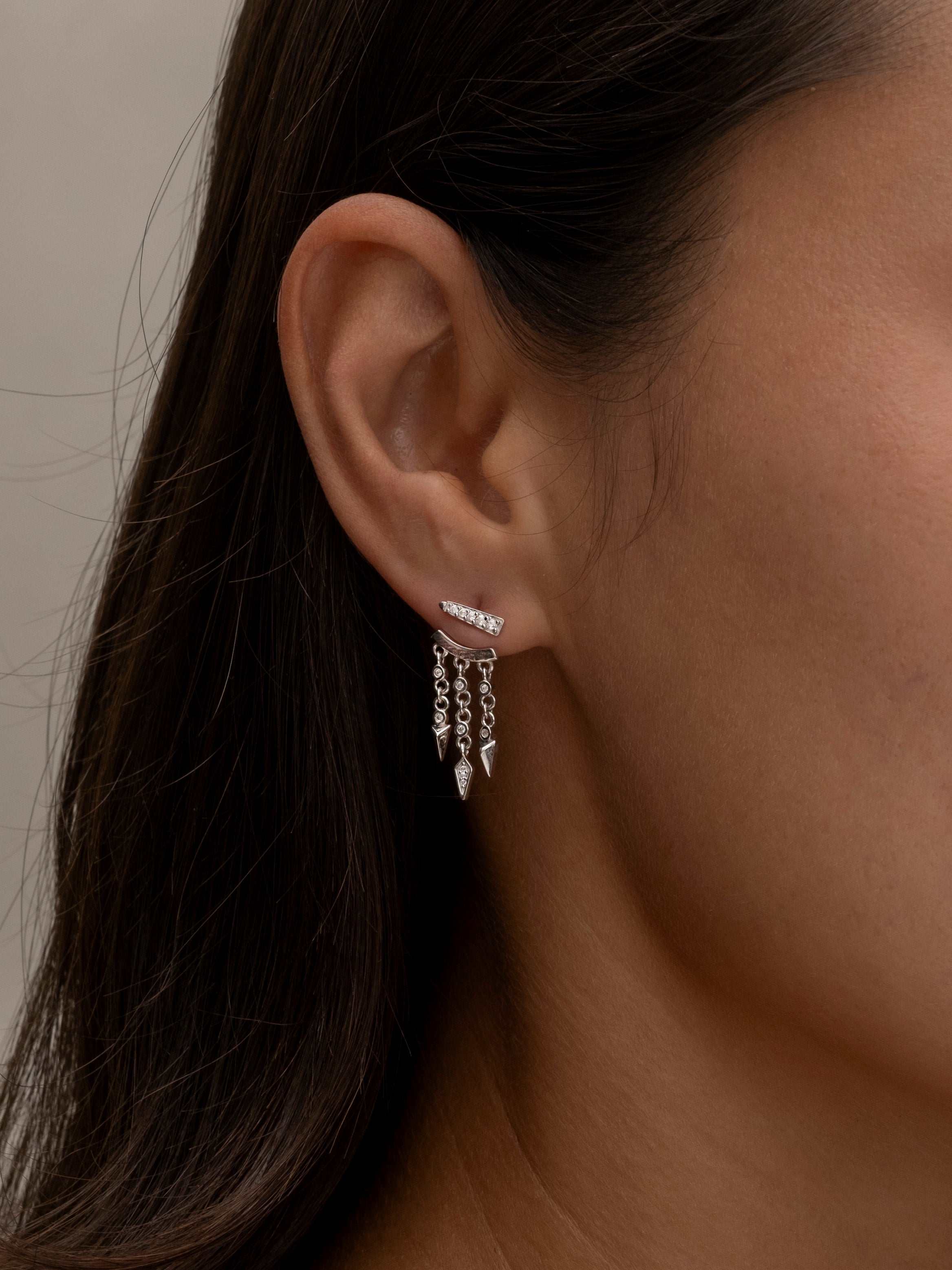 Side profile showing silver layered earrings on woman's ear.