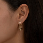 Side profile showing gold layered earrings on woman's ear.