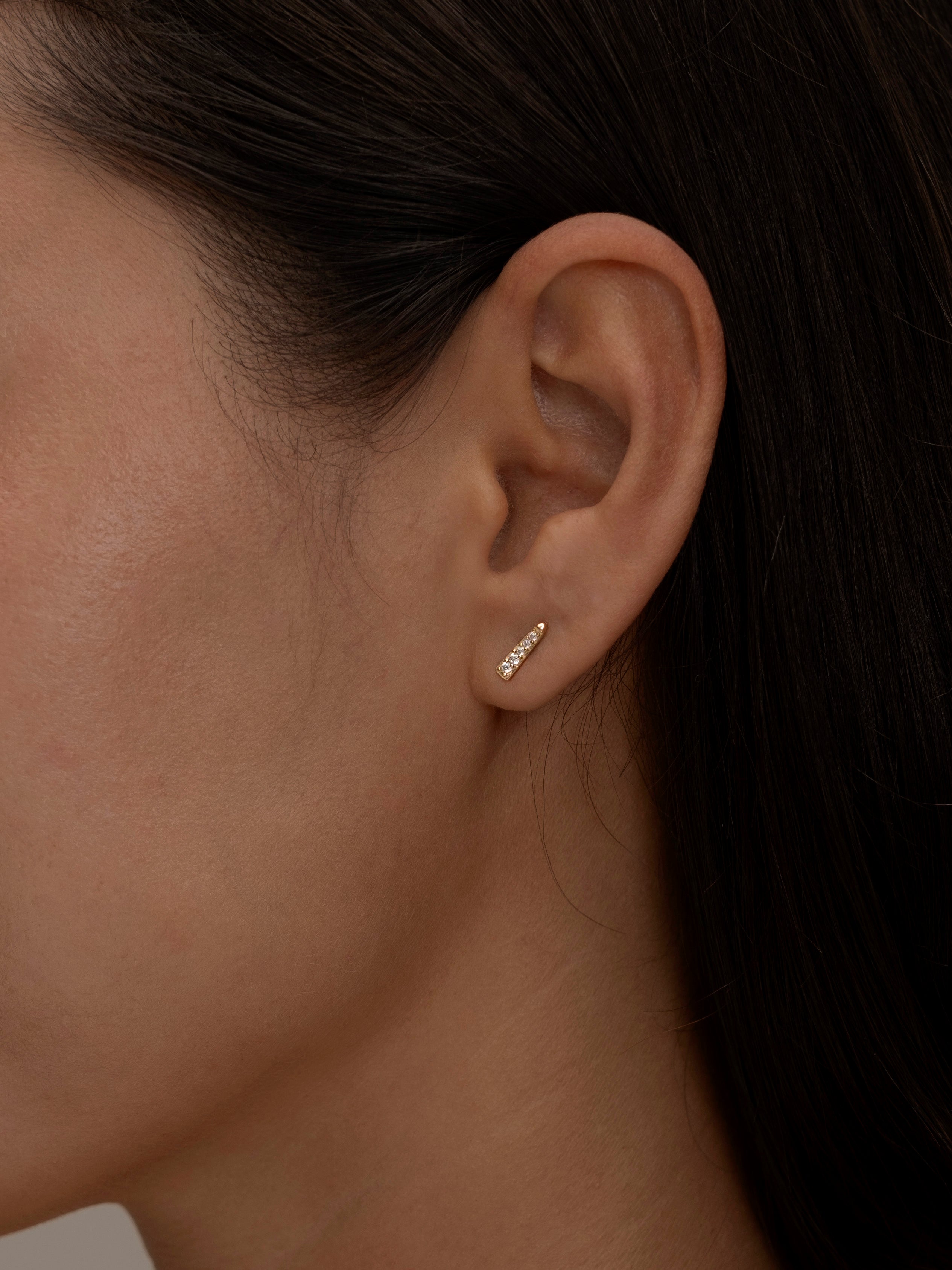 Gold Chloe stud earring on a woman's ear.