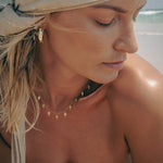 Woman wearing gold jewelry with a headscarf at the beach.