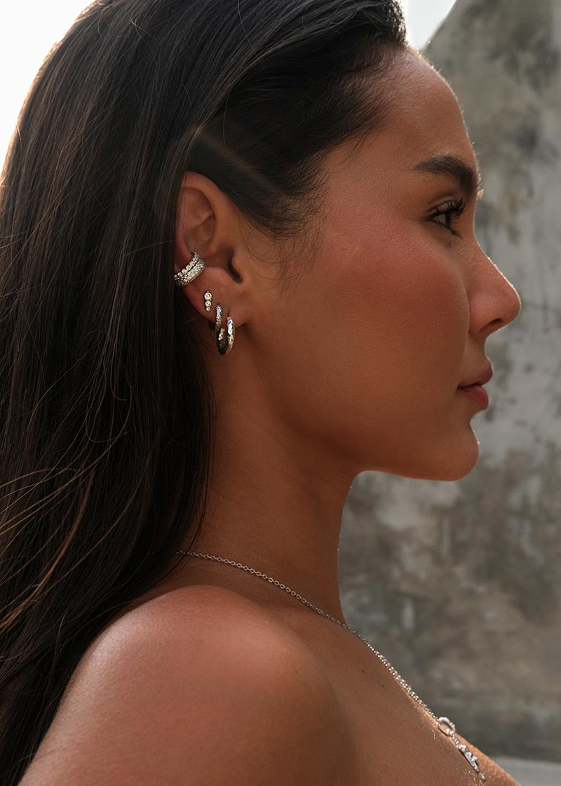 Portrait of a woman wearing diamond silver earrings and a silver necklace.