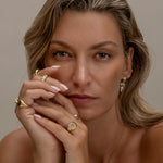 Woman with gold jewelry, including rings, necklace, and earrings.