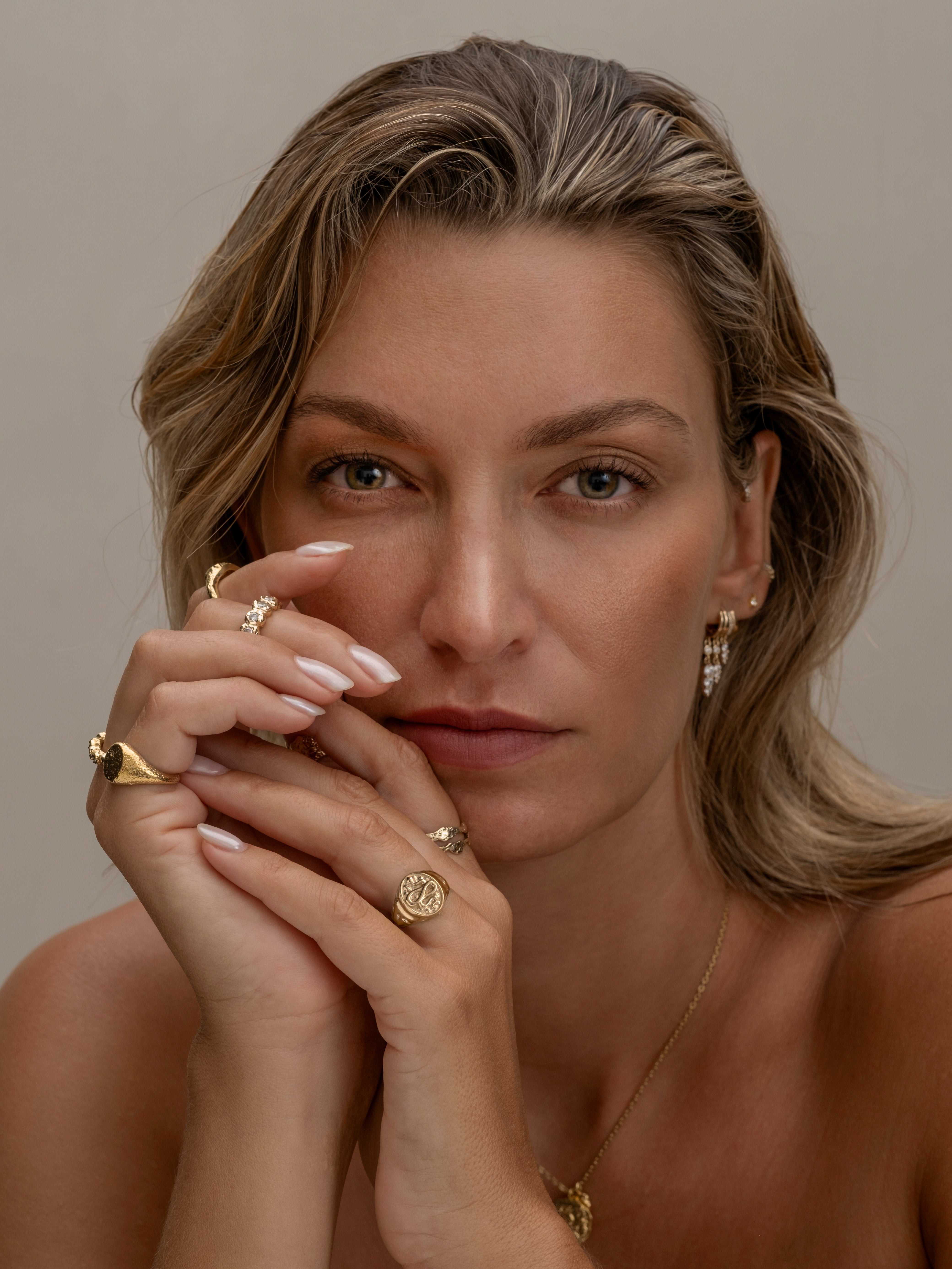 Woman with gold jewelry, including rings, necklace, and earrings.