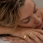 Woman with blonde hair wearing multiple gold rings.