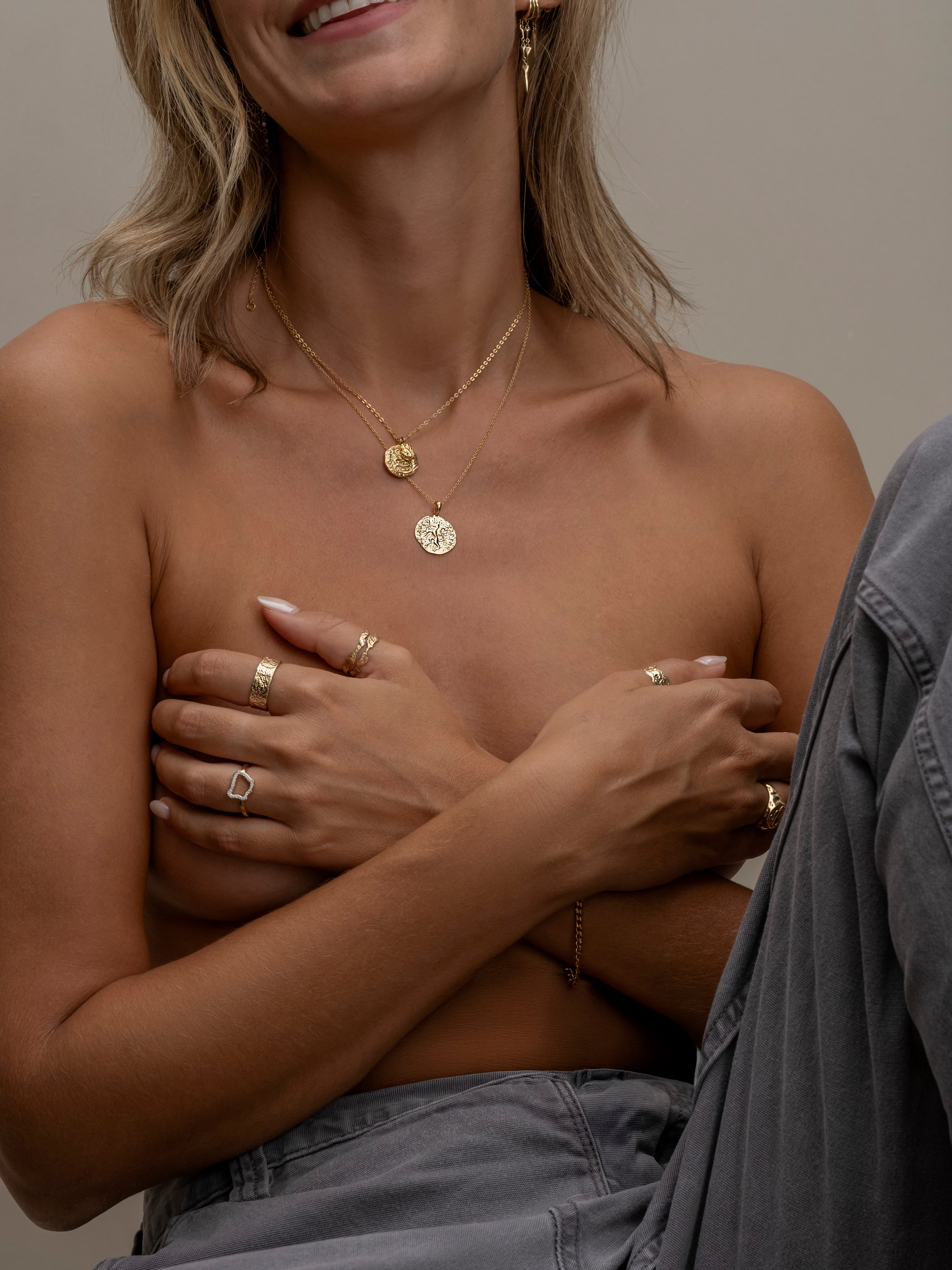 Smiling woman wearing layered gold coin necklaces.