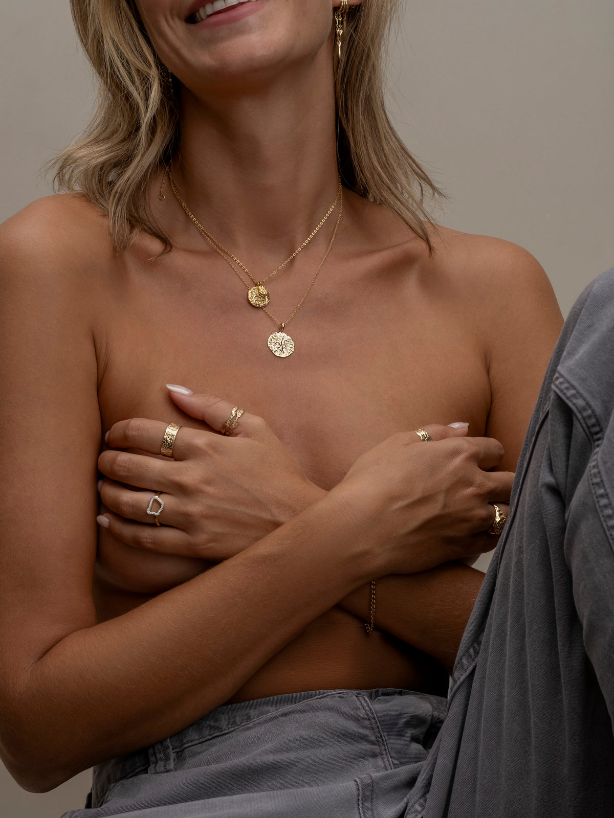 Smiling woman wearing layered gold coin necklaces.