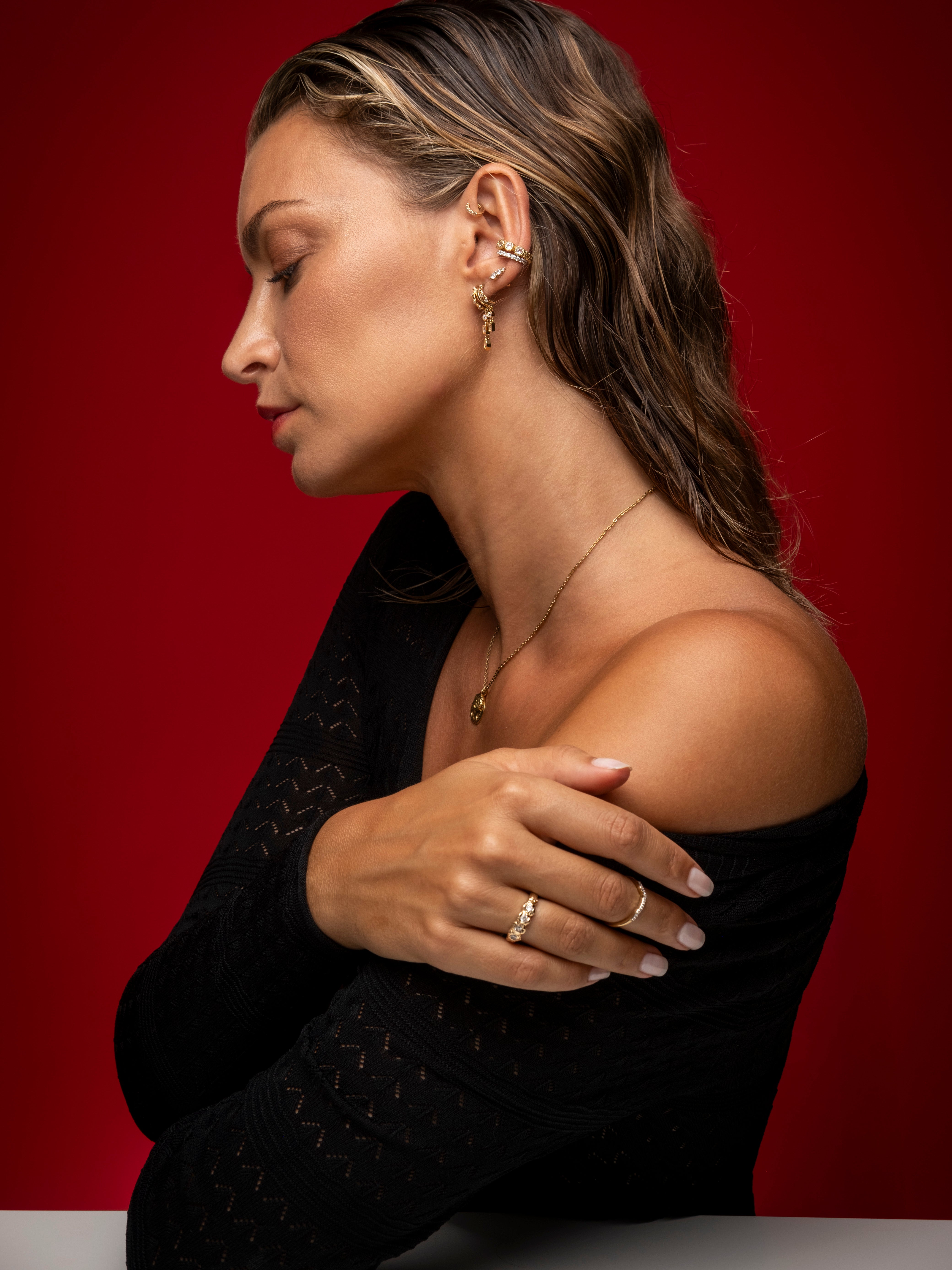 Gold-plated jewelry set featuring earrings, rings, and necklaces, styled for elegance. Available at Aaria London.