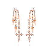Rose gold dangling earrings with cross and spike details.