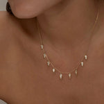 Close-up of gold Palma necklace with diamond-shaped charms on a woman.