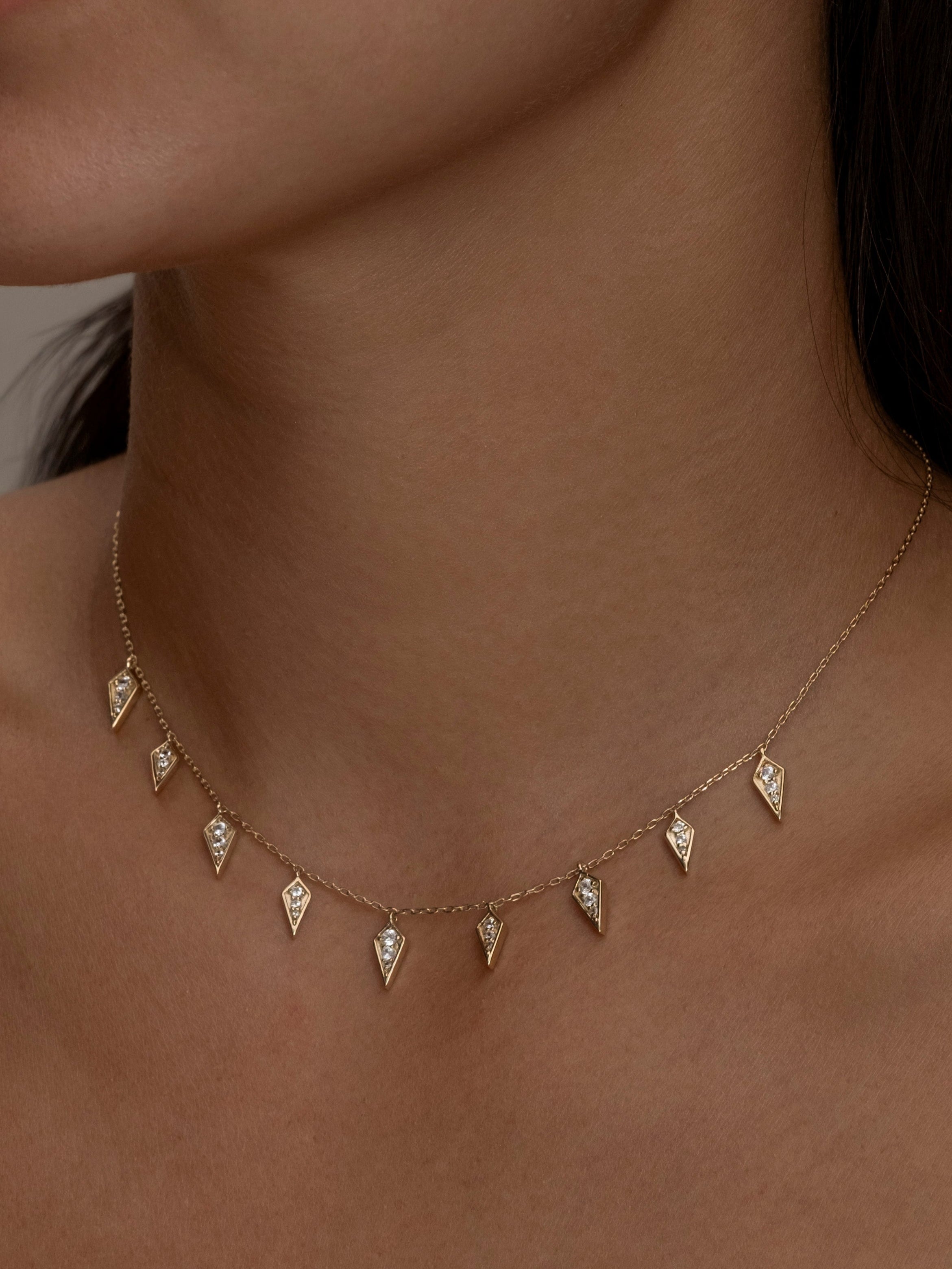 Gold Palma necklace with diamond-shaped charms on a woman.