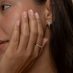 A women wearing delicate gold ring and earring with a subtle wavy diamond design. 