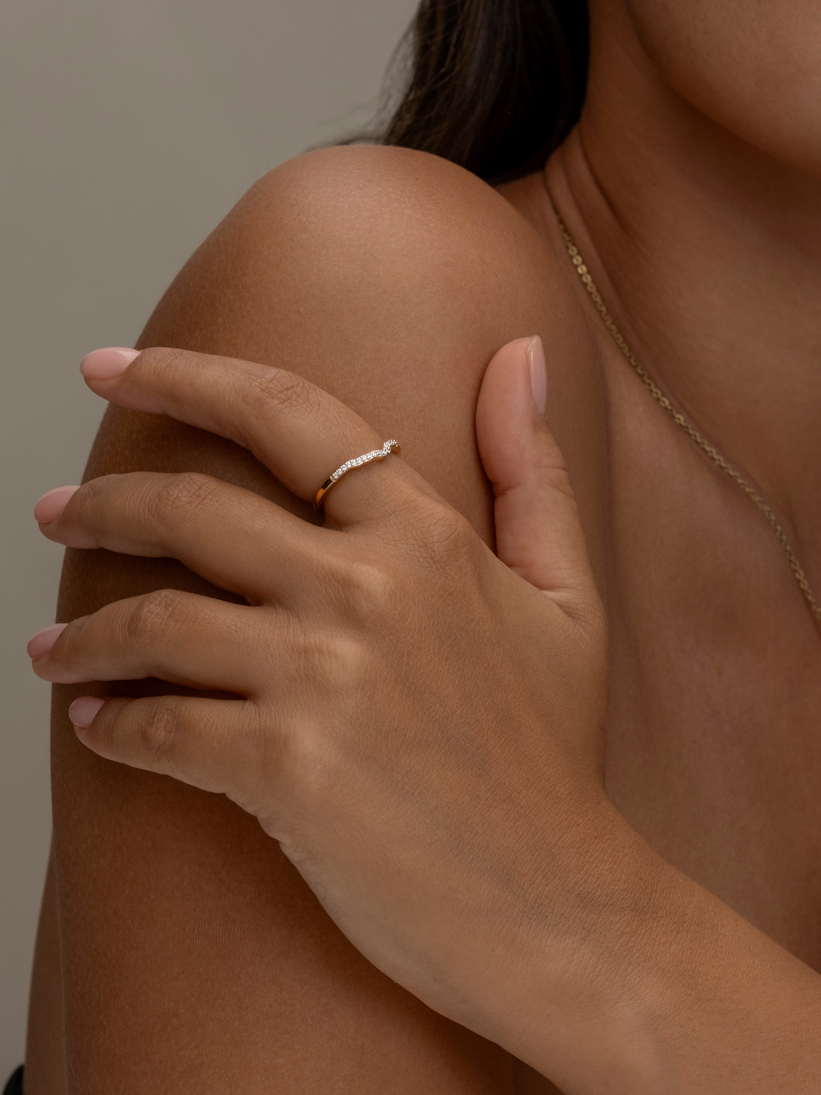 Elegant gold ring on hand with matching necklace