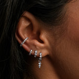 Close-up of a woman's ear adorned with multiple diamond earrings.