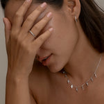 Woman covering face, wearing silver jewelry set.