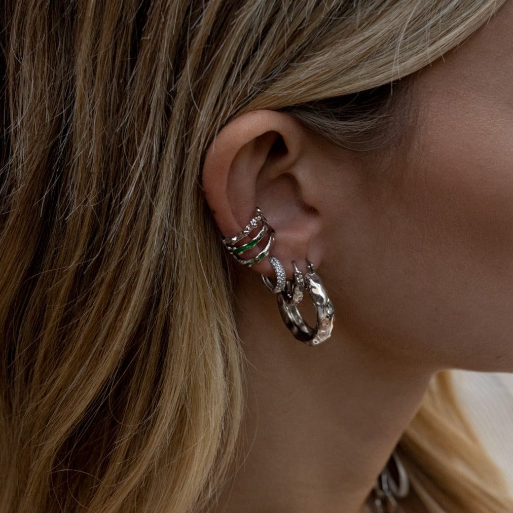 Woman with multiple silver hoop earrings stacked.