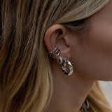 Woman with multiple silver hoop earrings stacked.