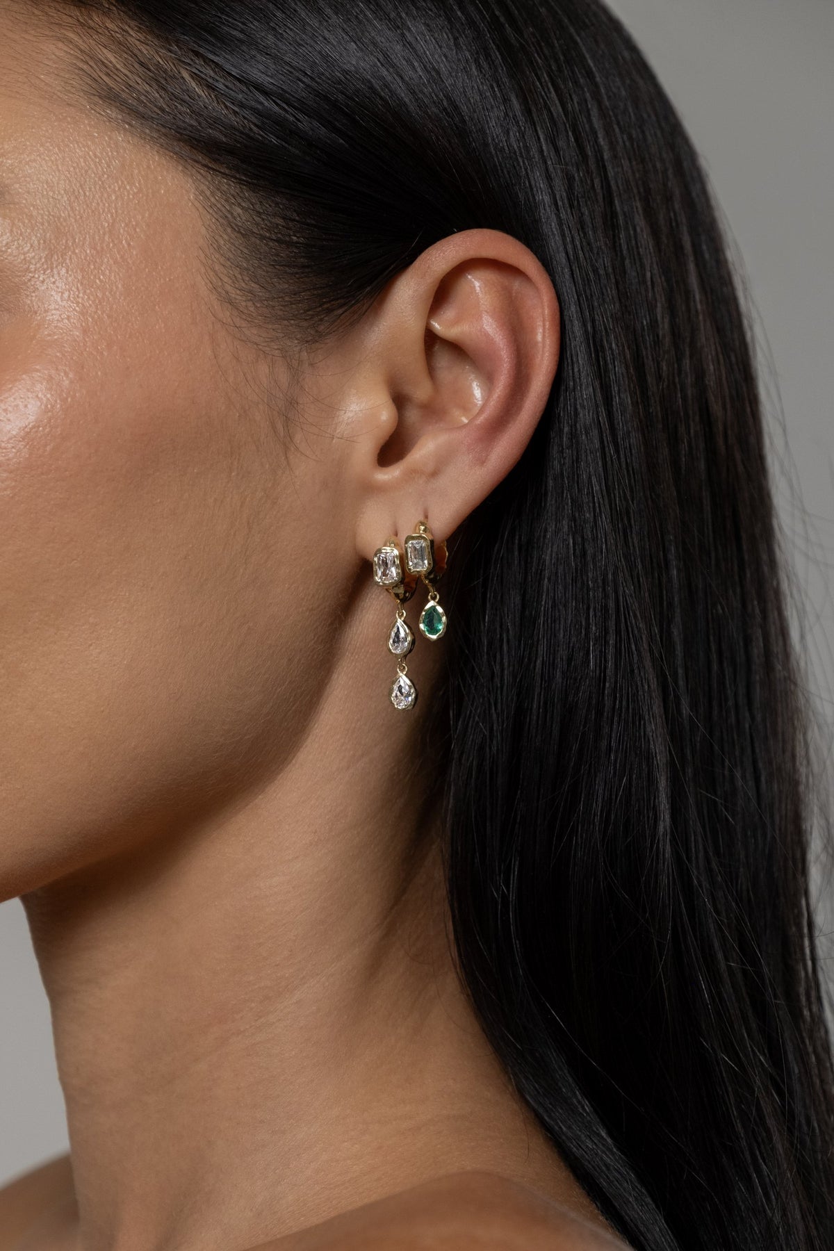 Model wearing Brooklyn Earrings (moissanite), Brooke Earrings (lab emerald)