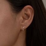 Minimalist gold halo hoop earring with diamond details.