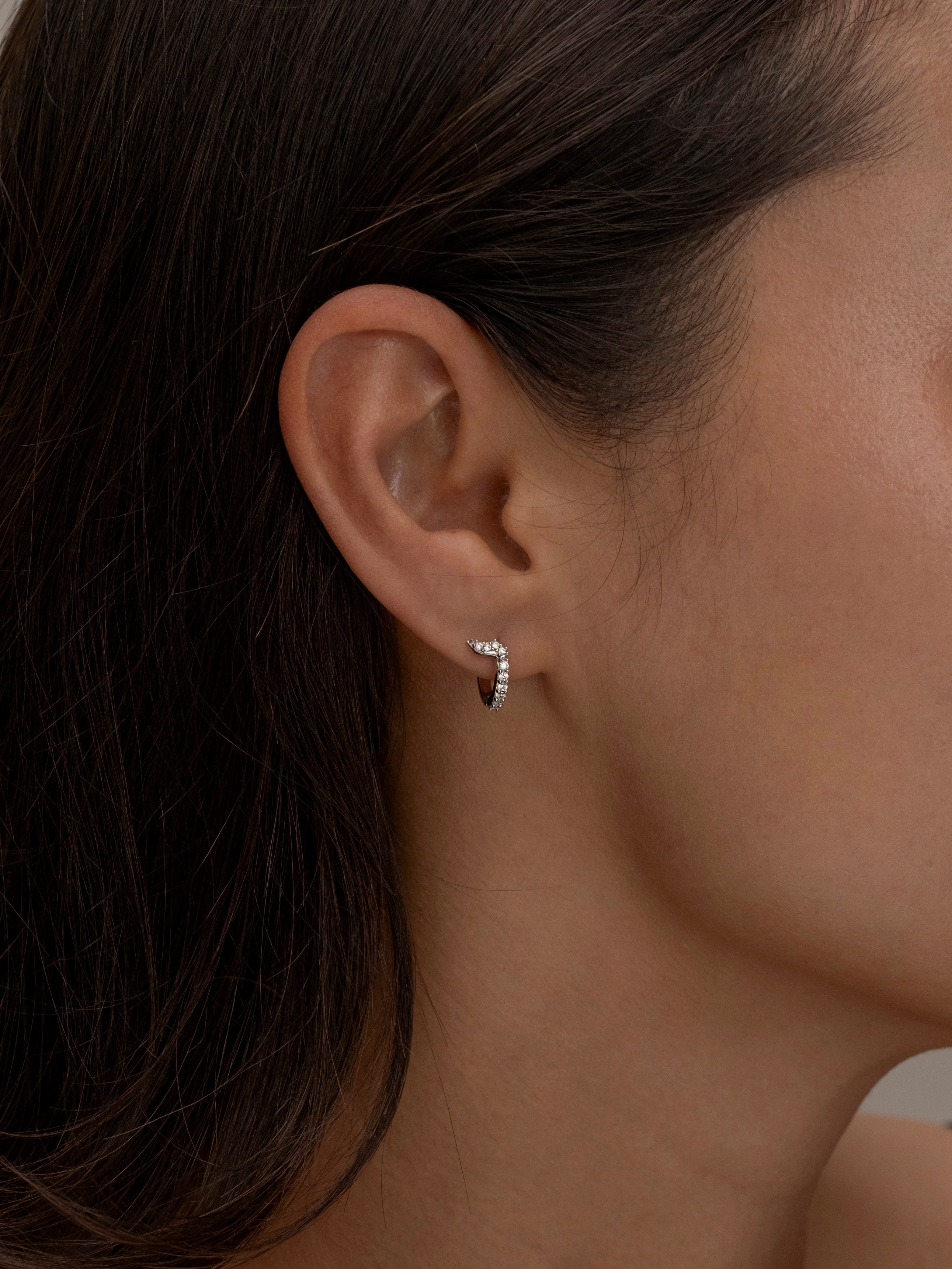 Minimalist silver hoop earring with diamond details.