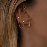 Close-up of an ear with tulum gold hoop earrings and a blurred background