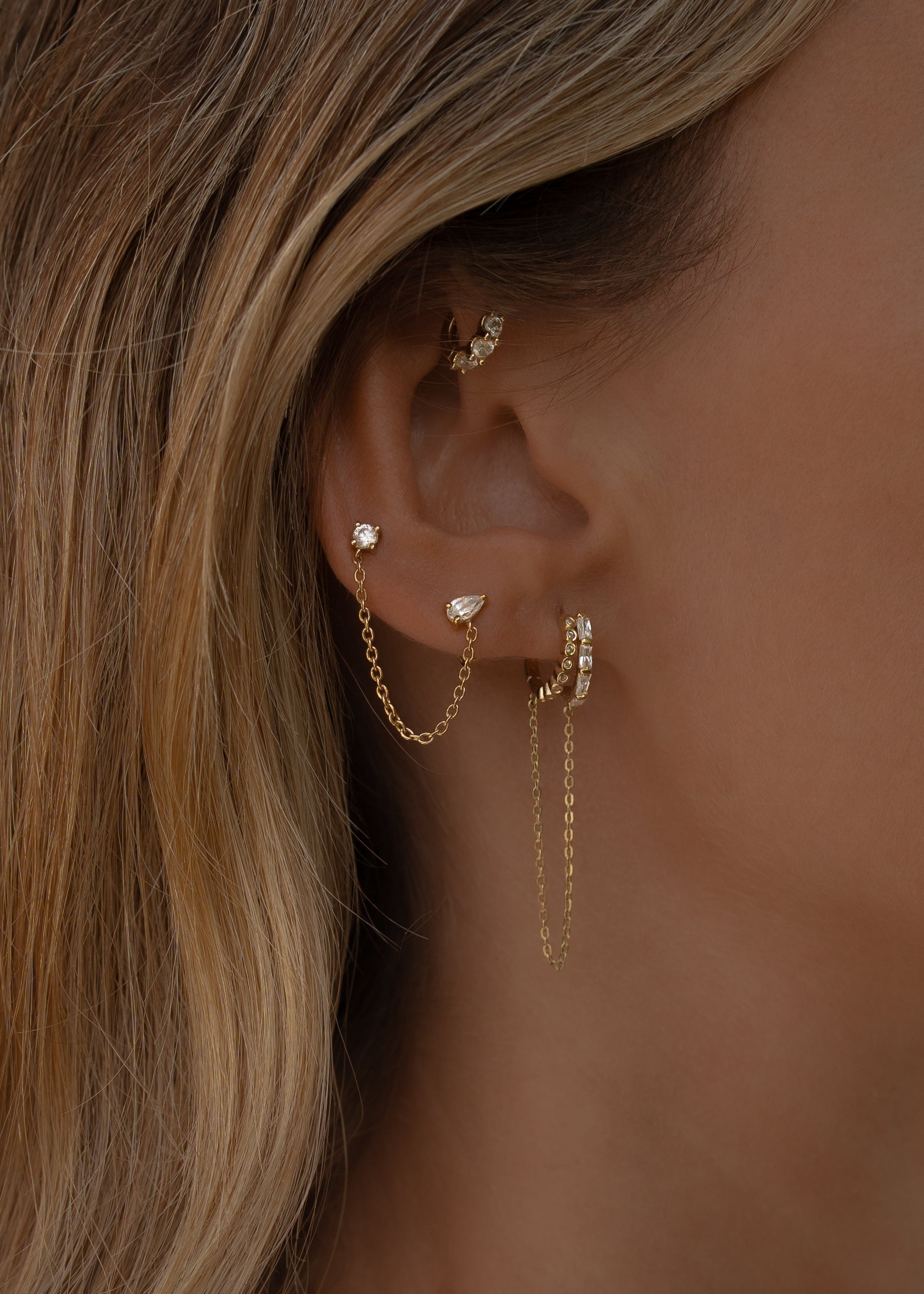 Close-up of an ear with tulum gold hoop earrings and a blurred background