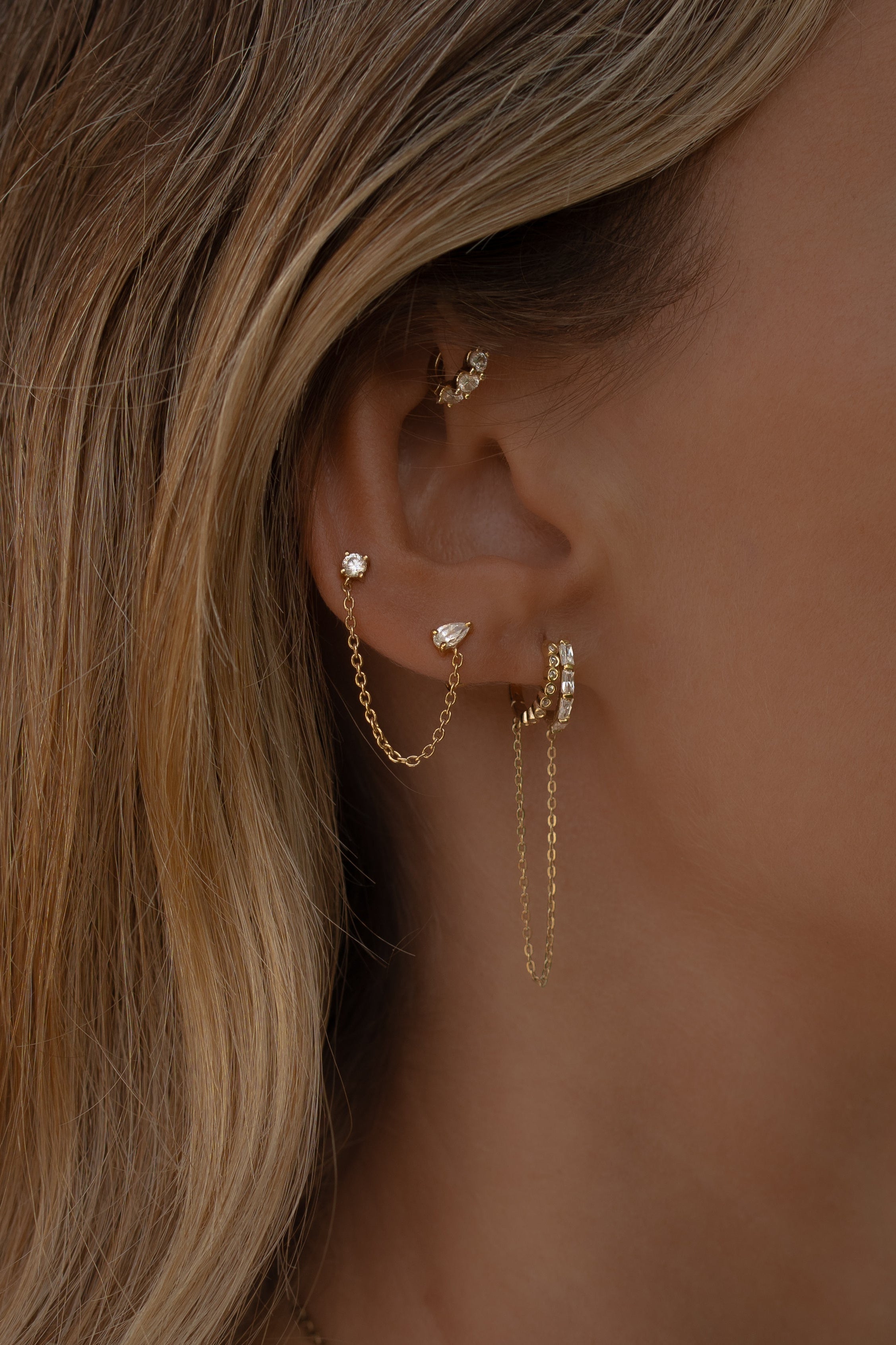 Close-up of an ear with tulum gold hoop earrings and a blurred background